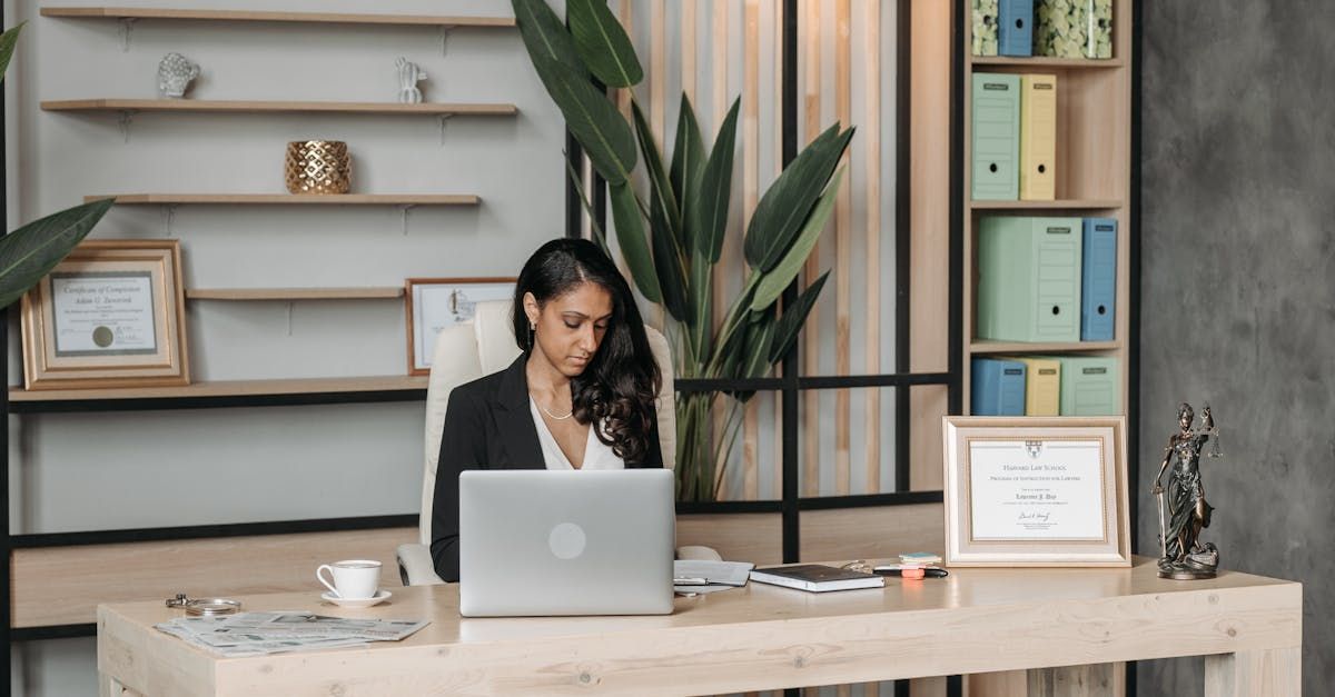 A woman is sitting at a desk in front of a laptop computer.