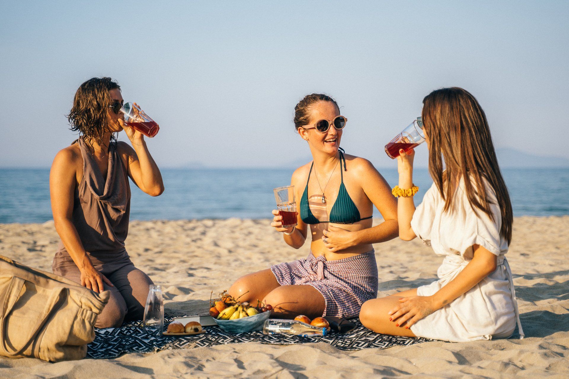 3 dames op het strand met een drankje en een hapje.