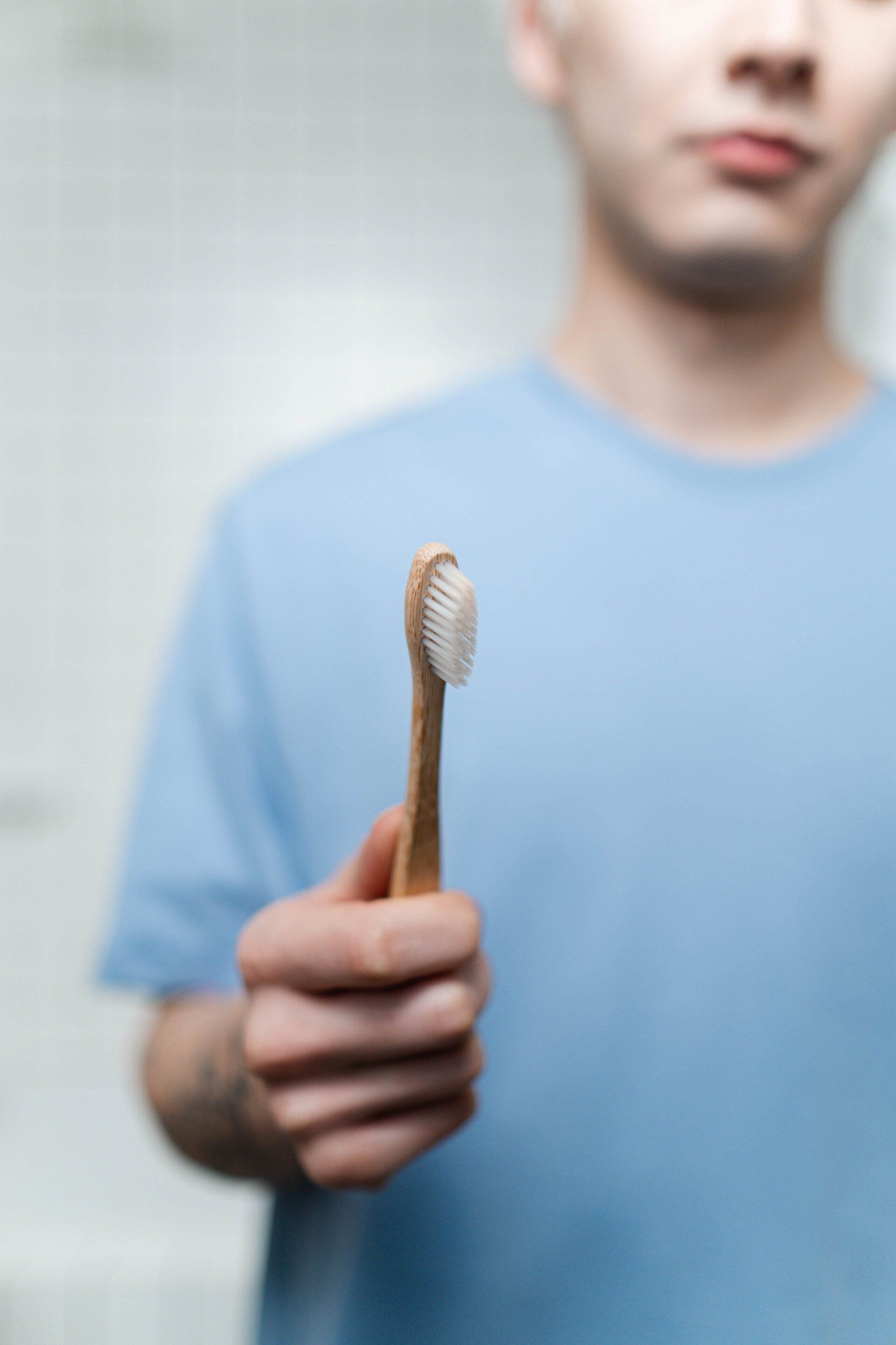A man is holding a wooden toothbrush in his hand.