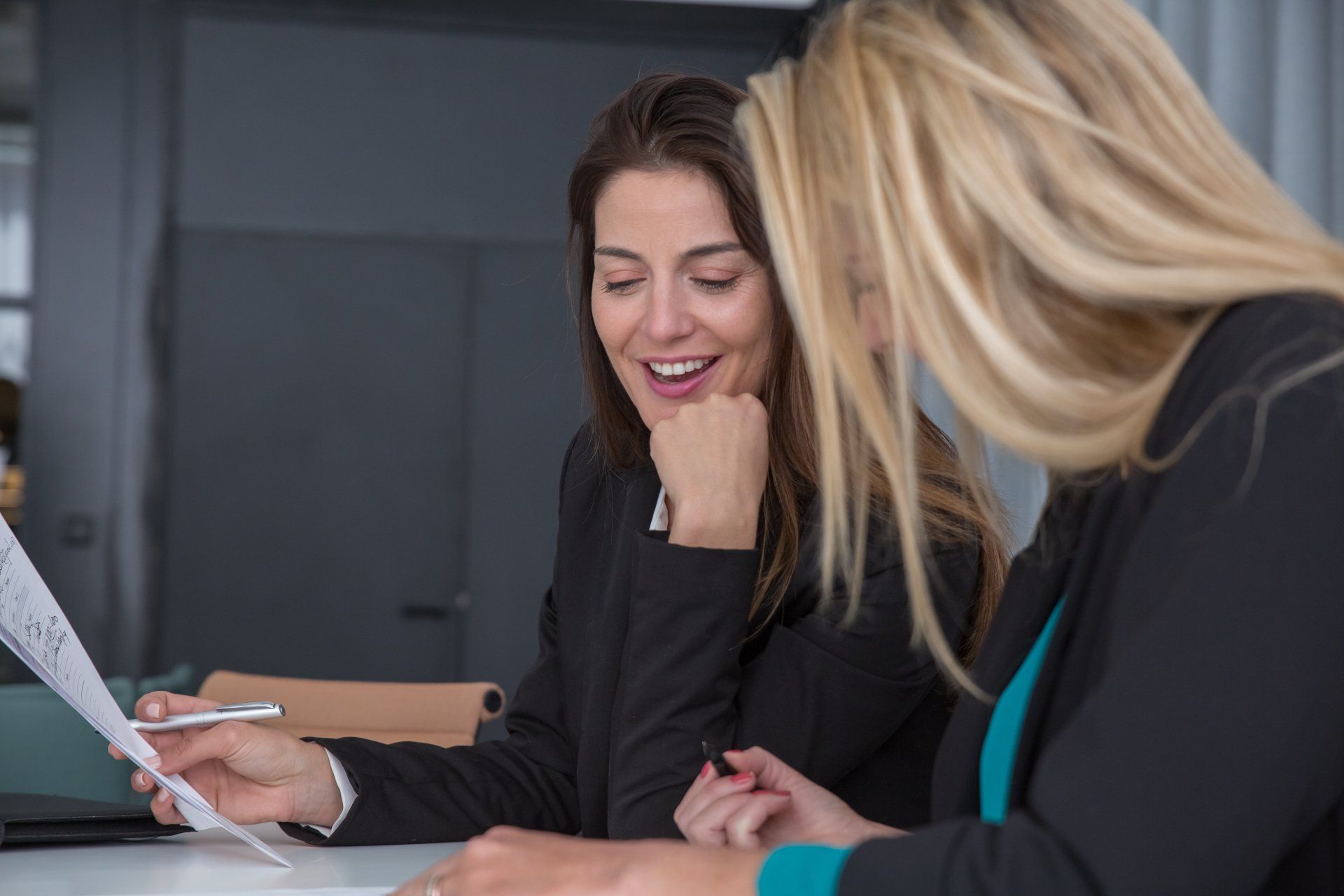 Two women sitting talking. One is writing.