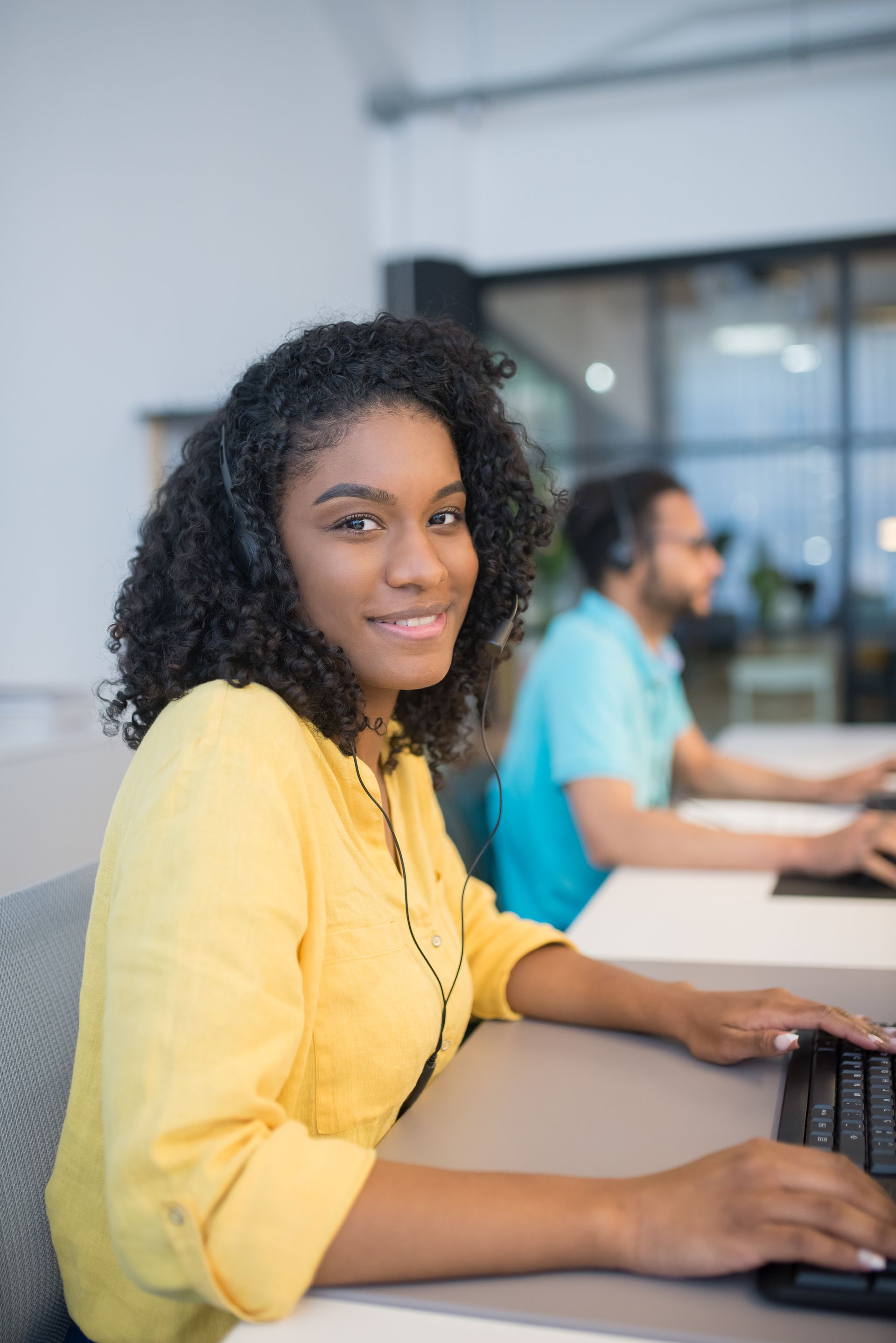 A woman wearing headphones is sitting at a desk using a computer.