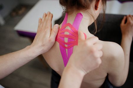 A woman is getting a massage with kinesio tape on her neck.