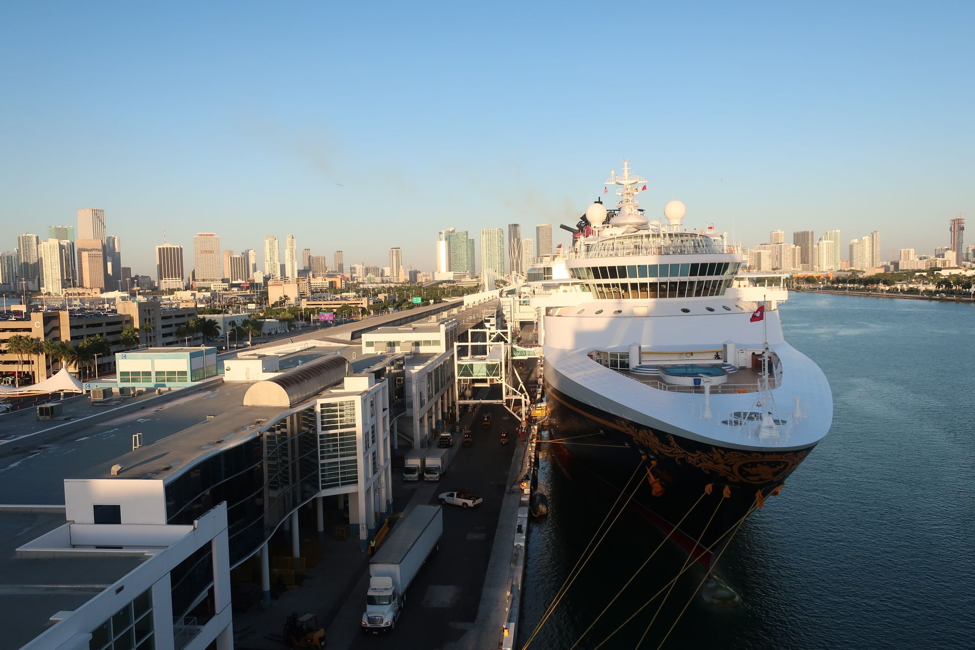 A cruise ship is docked in a harbor with a city in the background