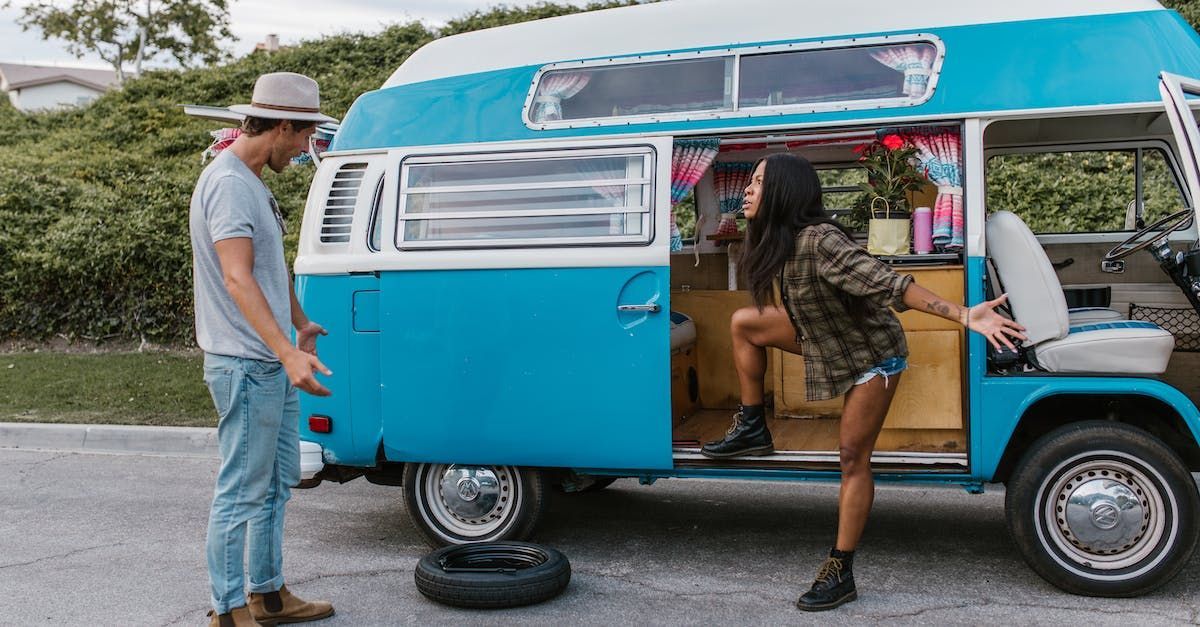 A couple on the road with a flat tire on their VW bus