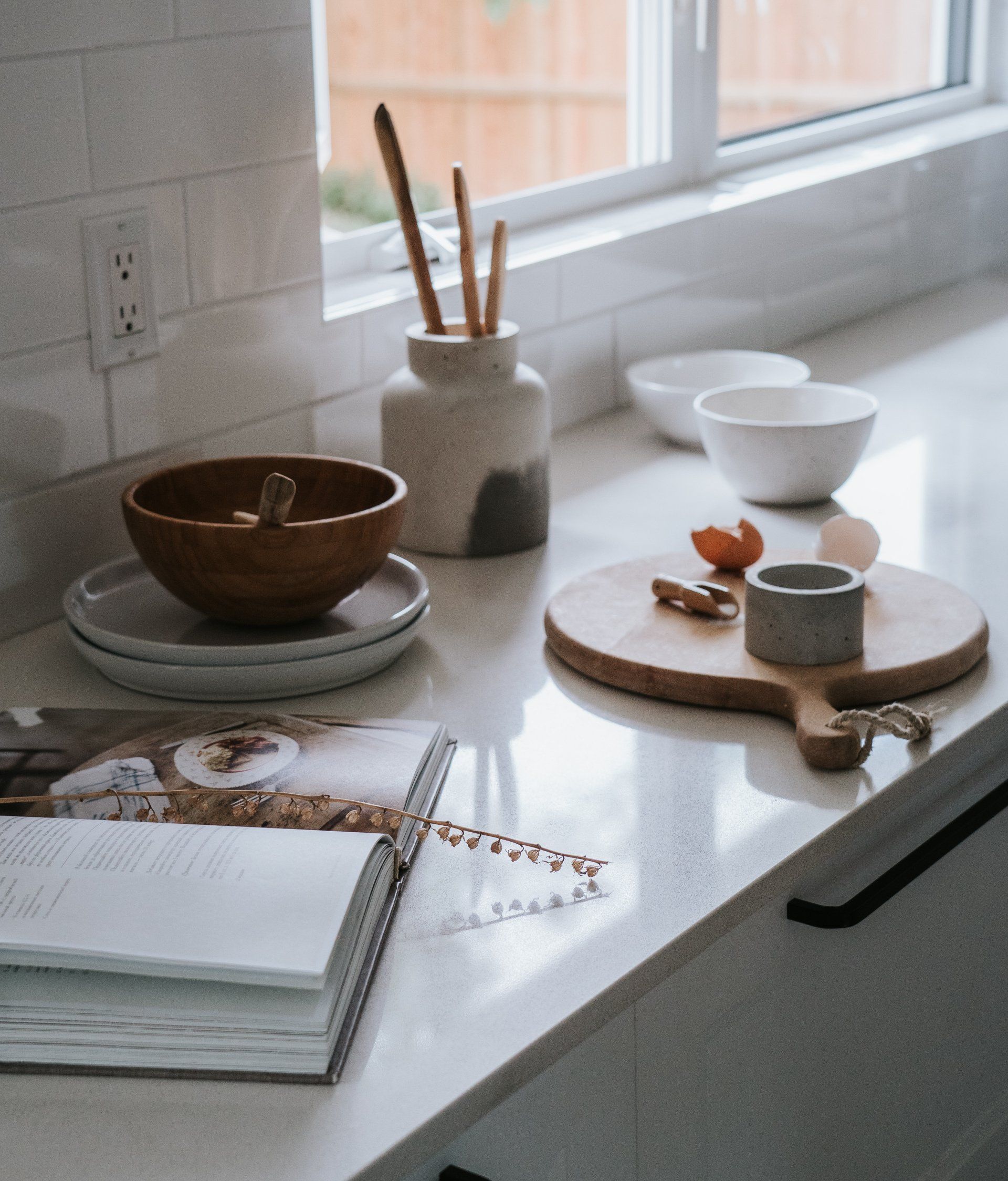A quartz-look countertop with a recipe book and bowls atop it in front of a subway tile backsplash