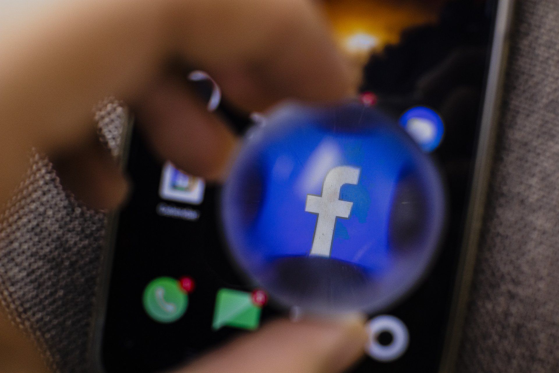 una persona tiene in mano un telefono cellulare con un'icona di facebook sullo schermo .