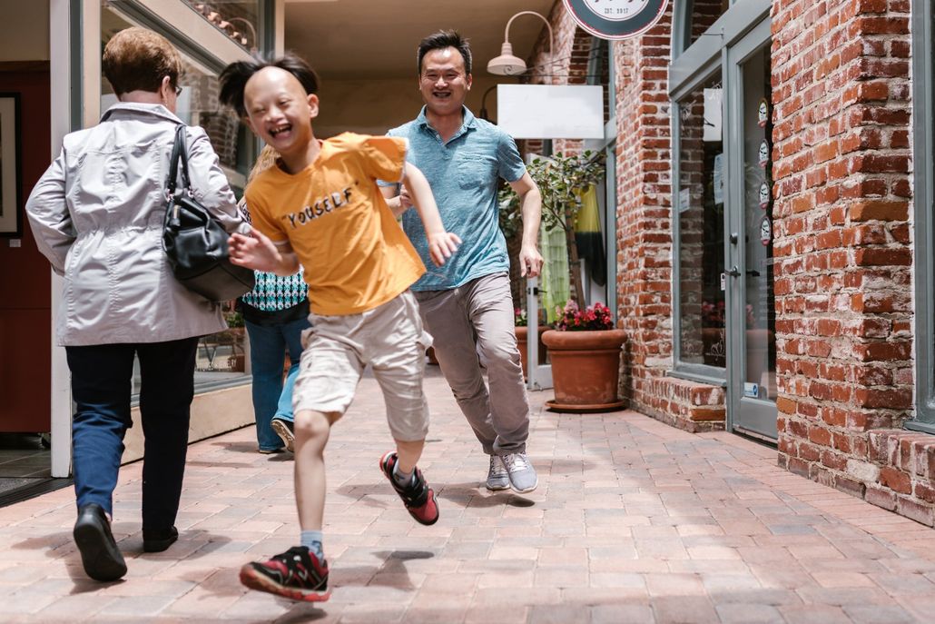 A group of people are walking down a sidewalk in a shopping mall.