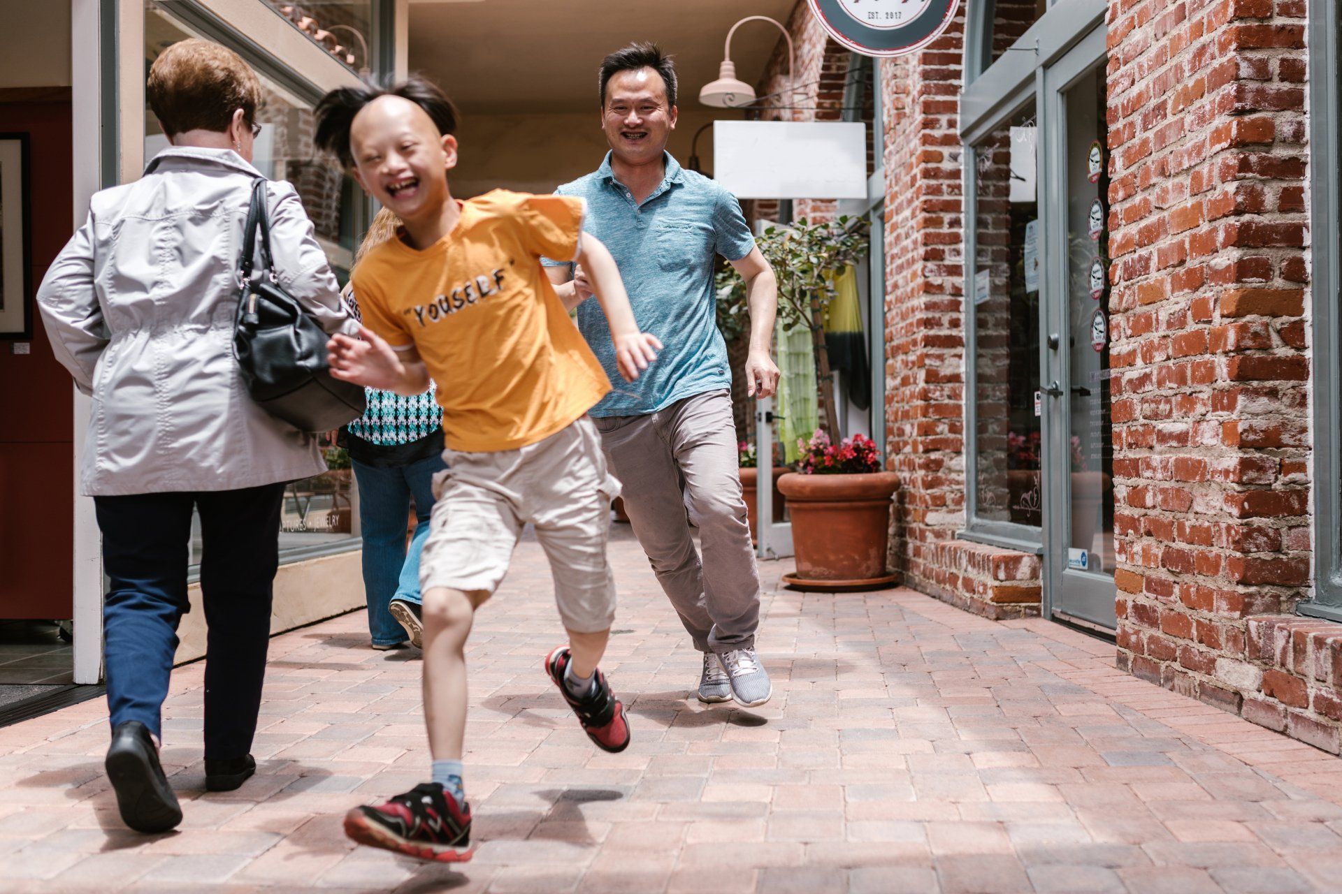 A group of people are walking down a sidewalk in a shopping mall.