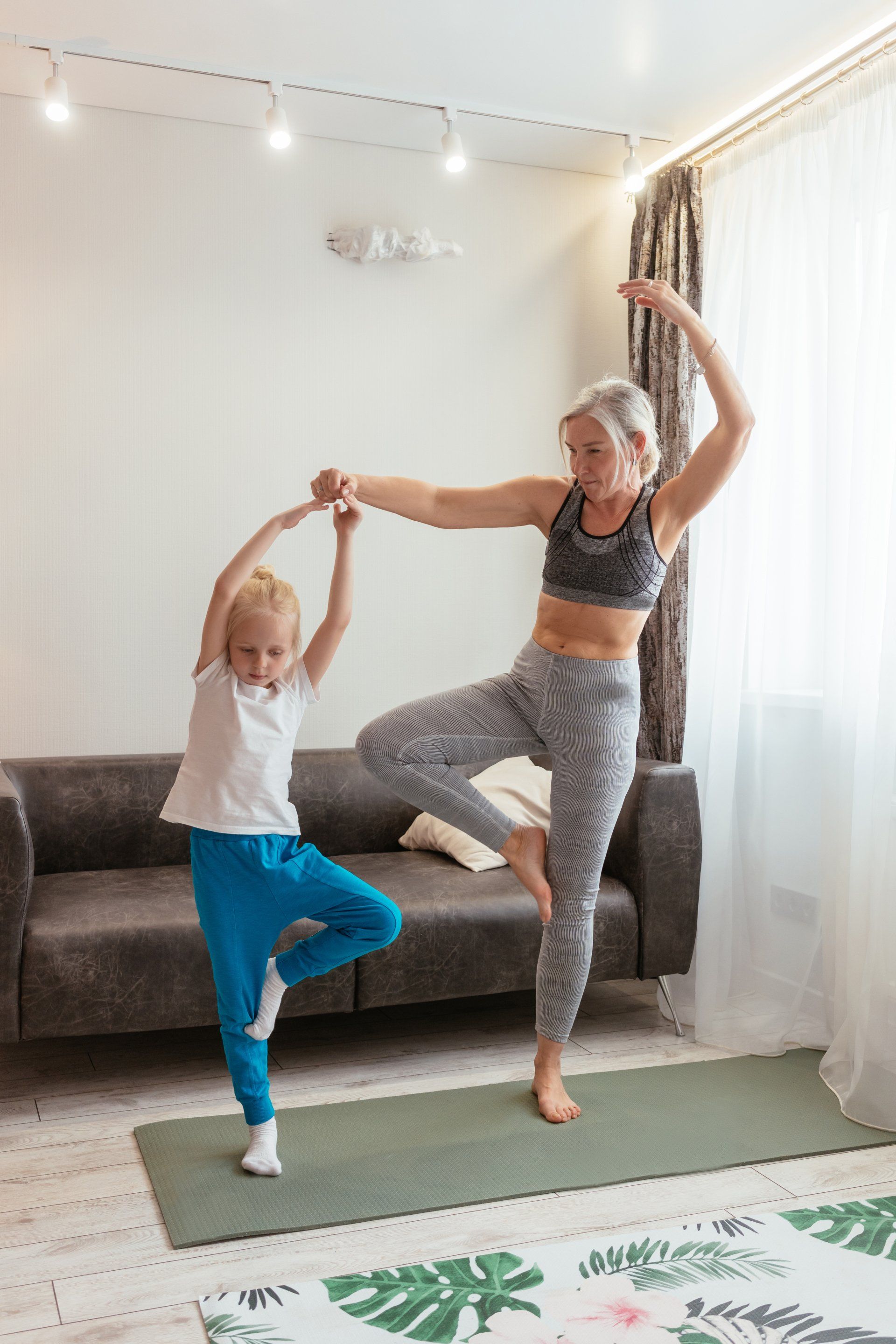 A woman and a little girl are doing yoga together in a living room.