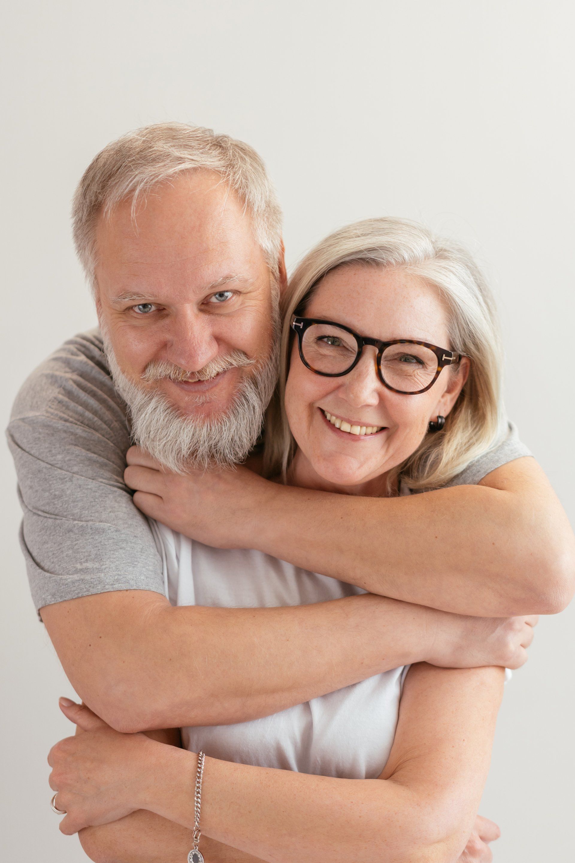 A man and a woman are hugging each other and smiling for the camera.