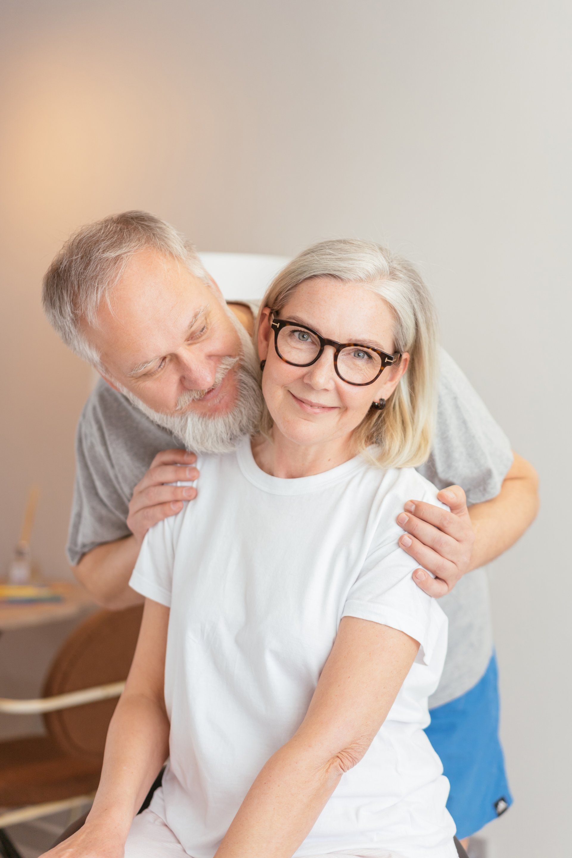 An older man is giving an older woman a massage.