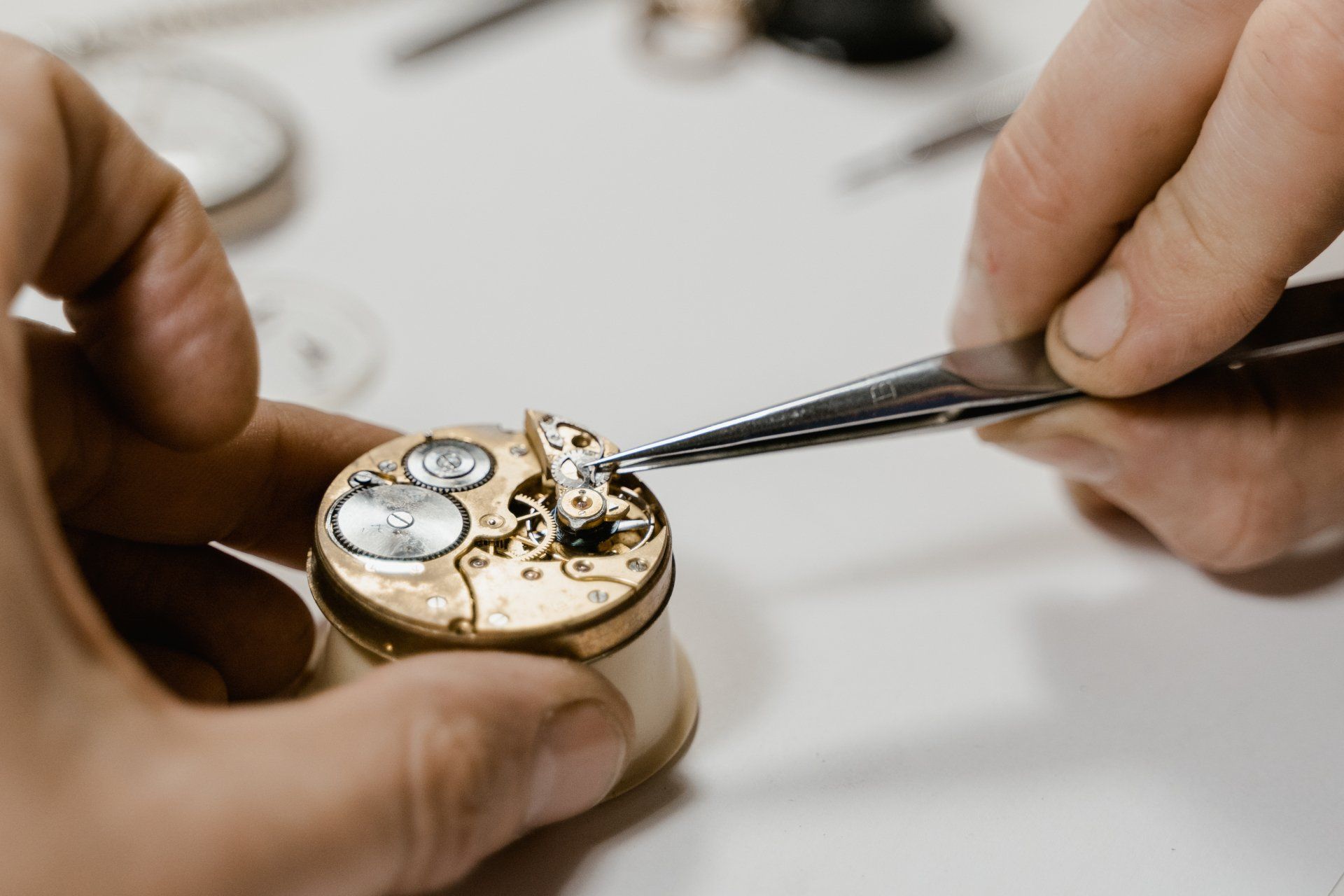 A person is fixing a watch with tweezers.