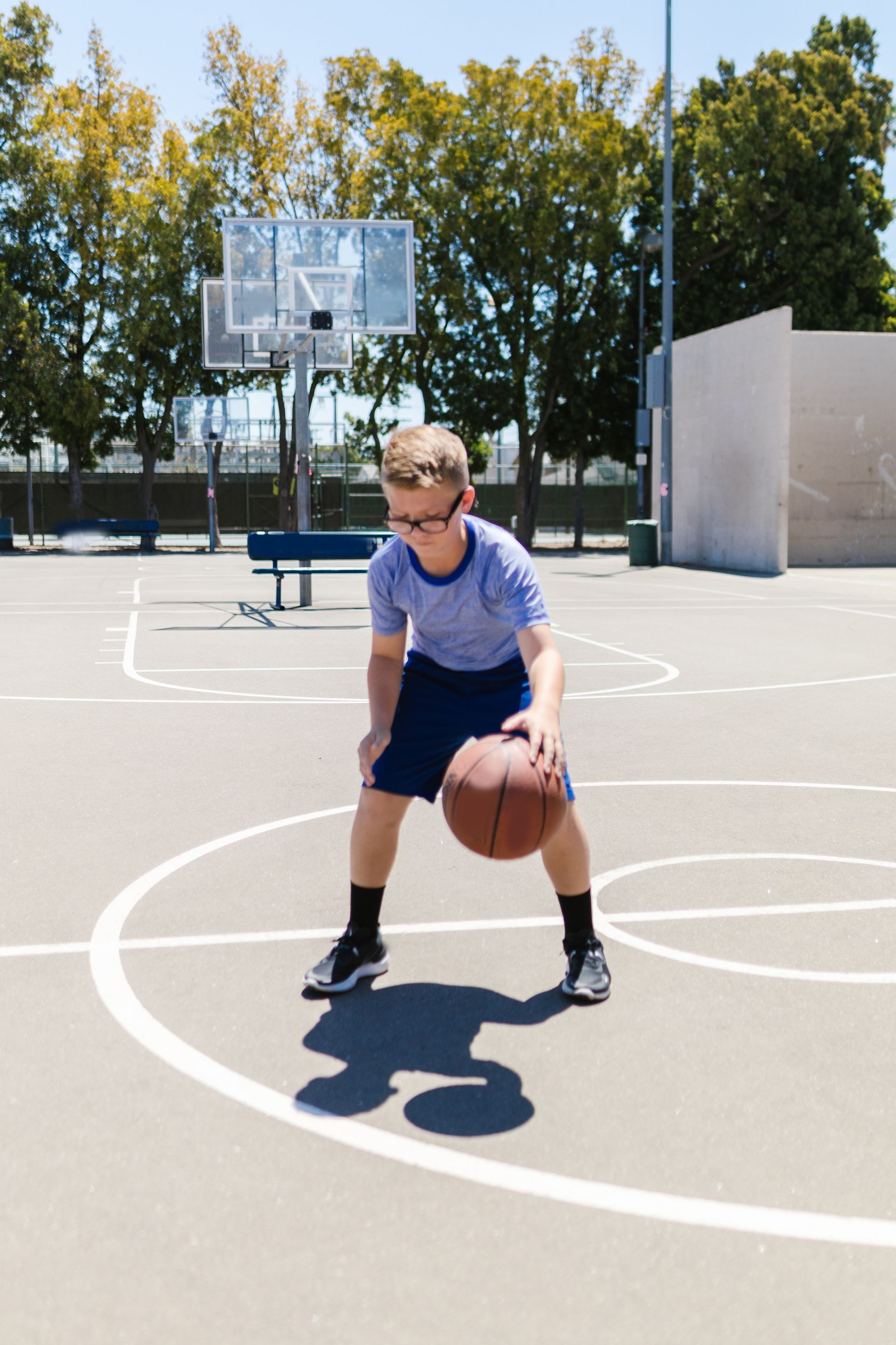 A young boy is playing basketball on a court.
