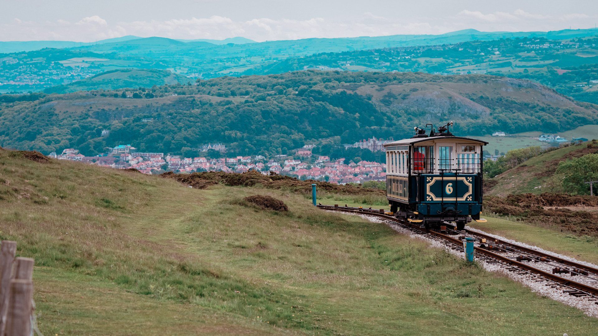 A train is going down the tracks on top of a hill.