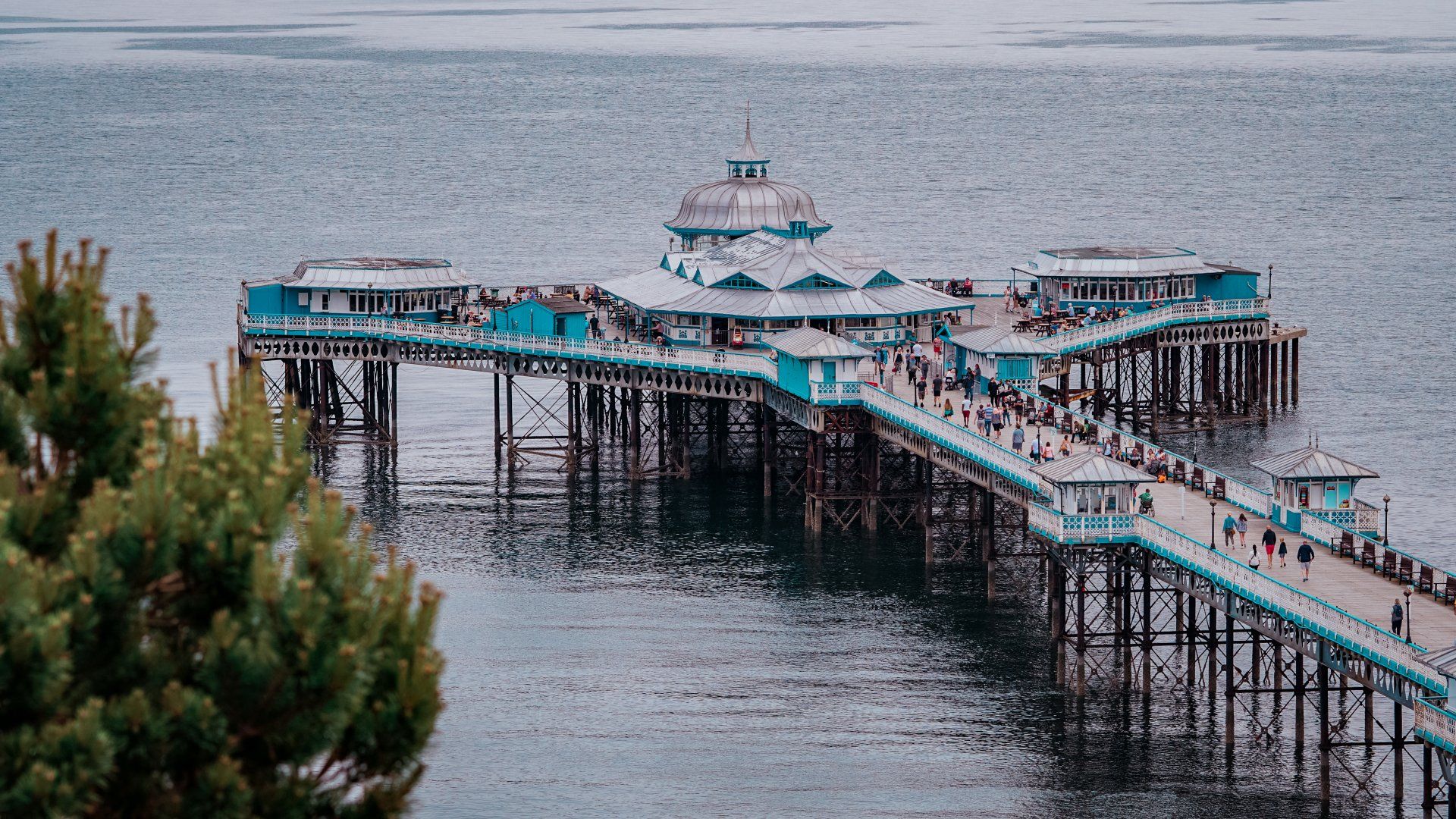 A pier in the middle of the ocean with people walking on it.