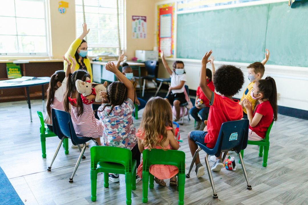 Image of children raising hands in a classroom