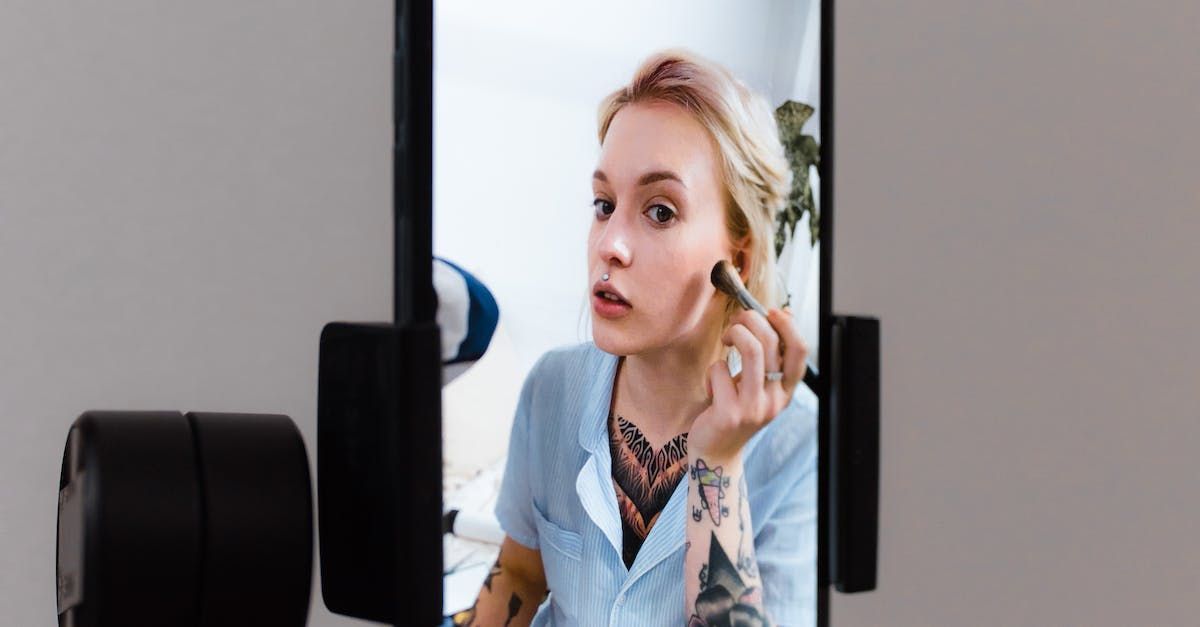 A woman is applying makeup to her face in front of a mirror.