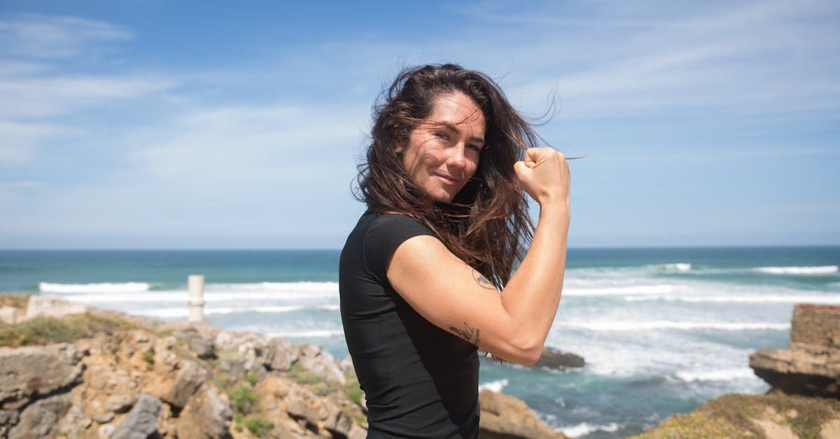 Woman Is Standing on A Rock Near the Ocean Flexing Her Muscles