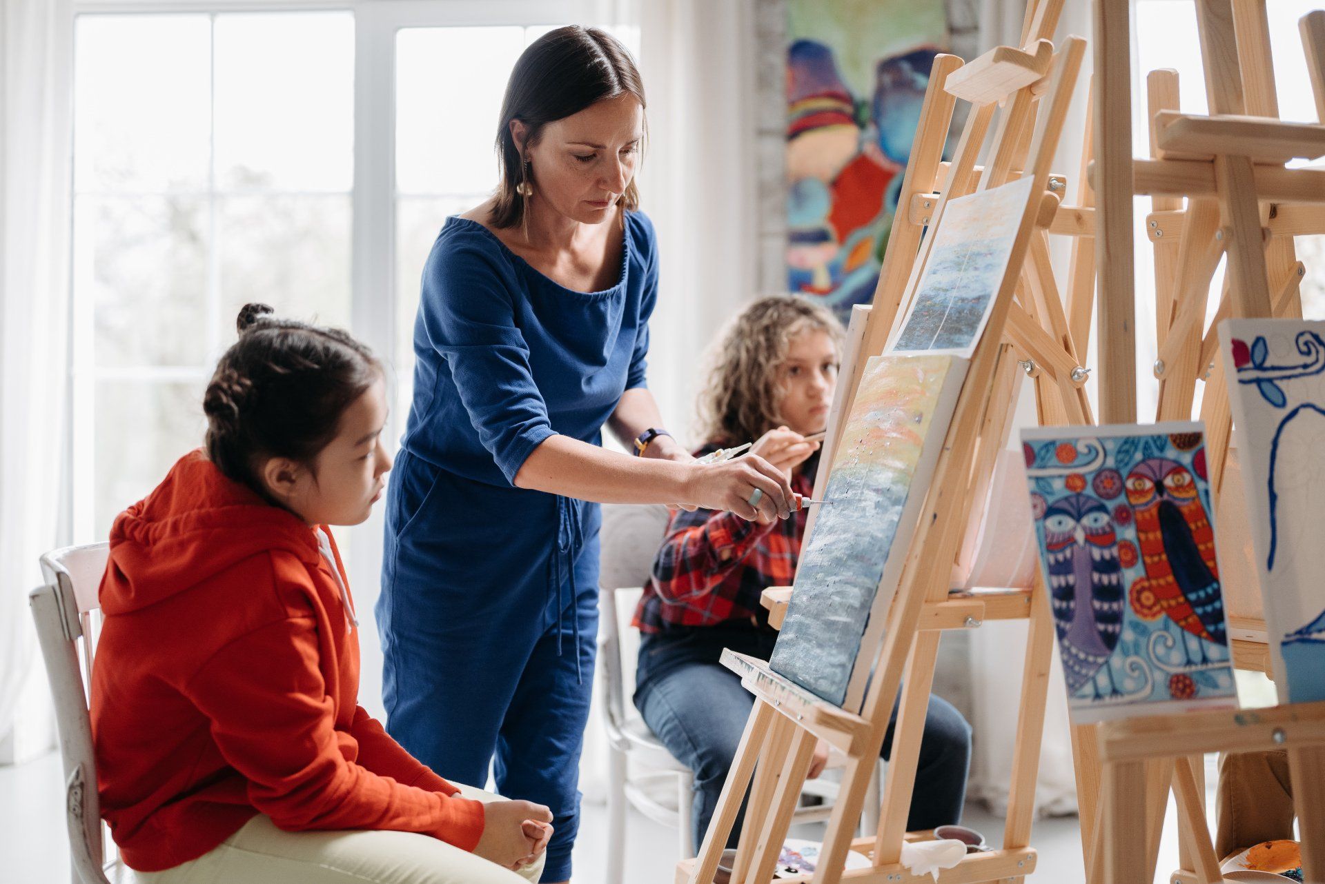 Women helping child paint a paining on an isle.