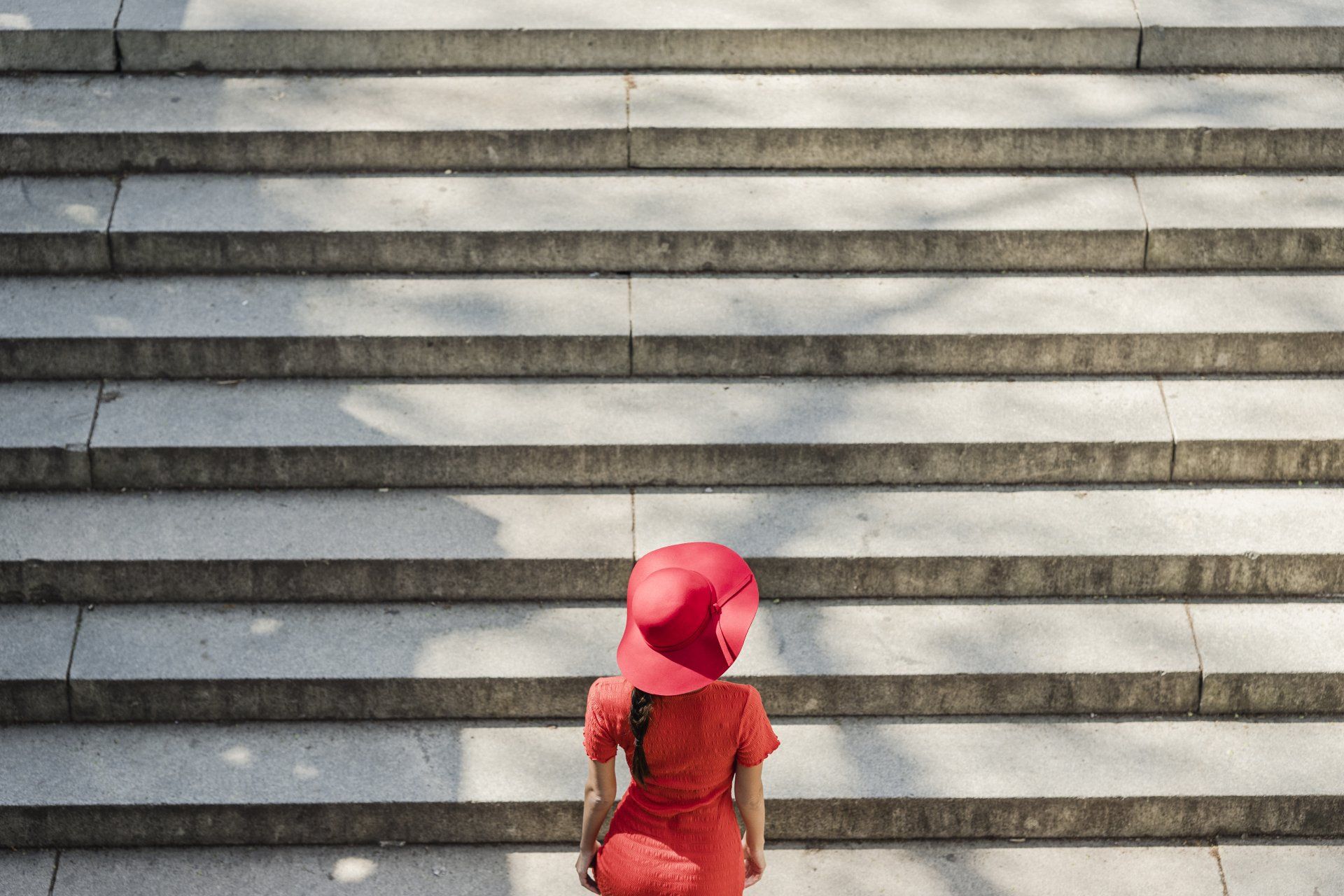woman in red going up the sunlit concrete stairs