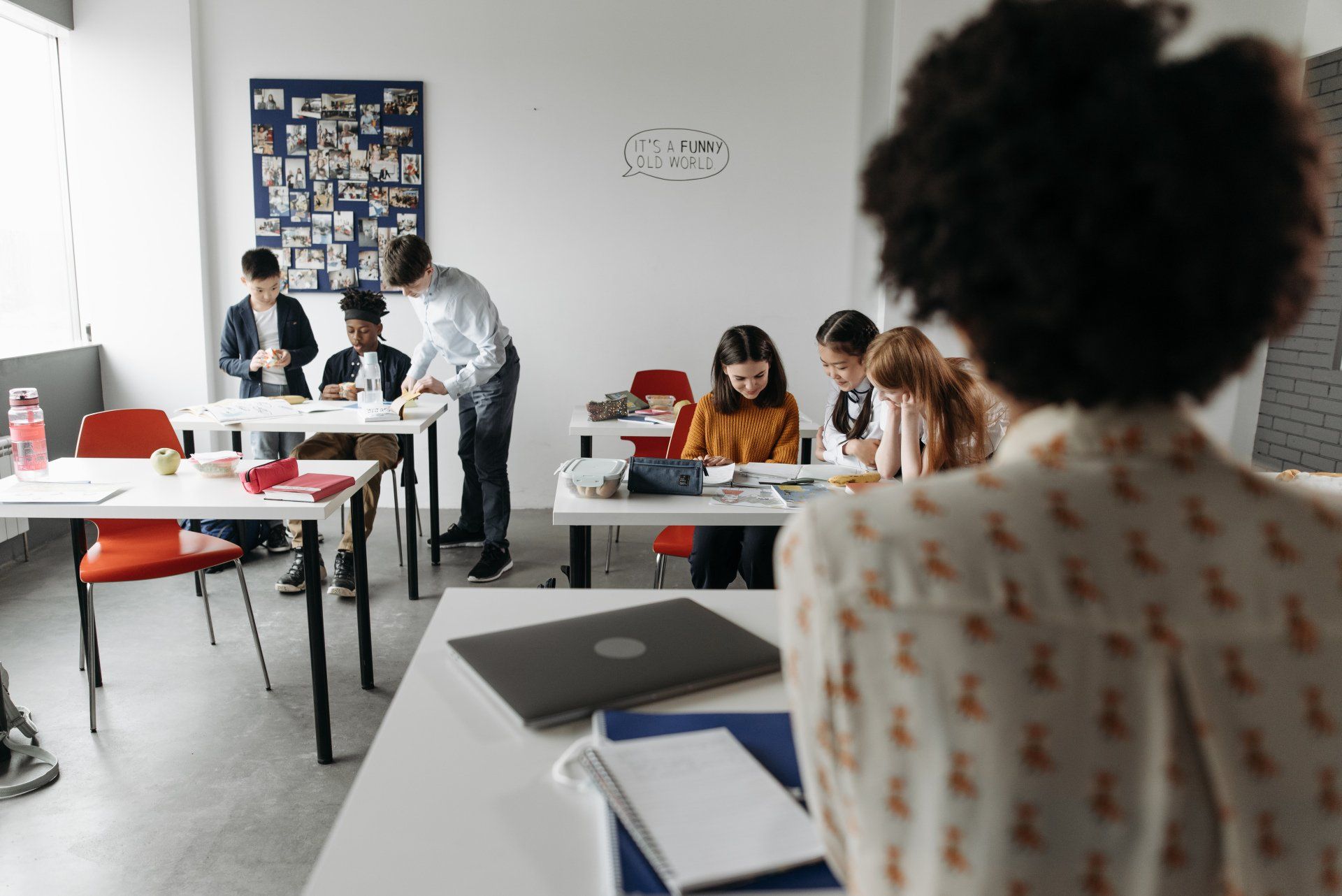 A group of people are sitting at tables in a classroom.