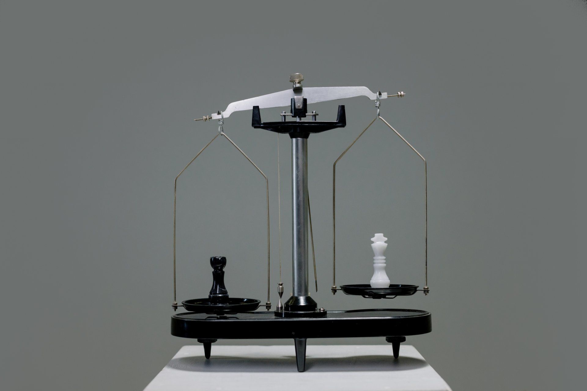 a scale with two chess pieces on it on a table.