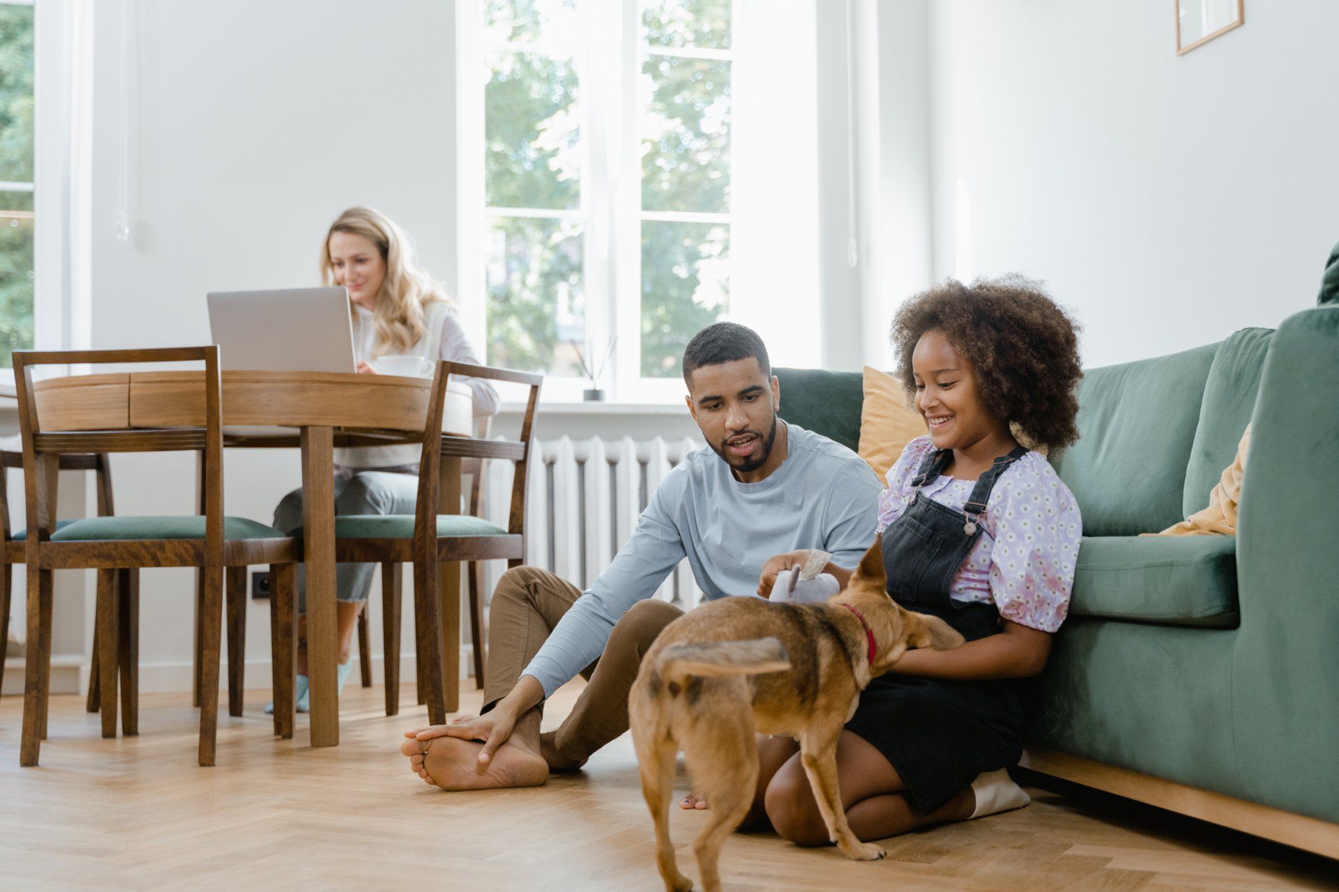 a man and woman are sitting on the floor with a dog in a living room .