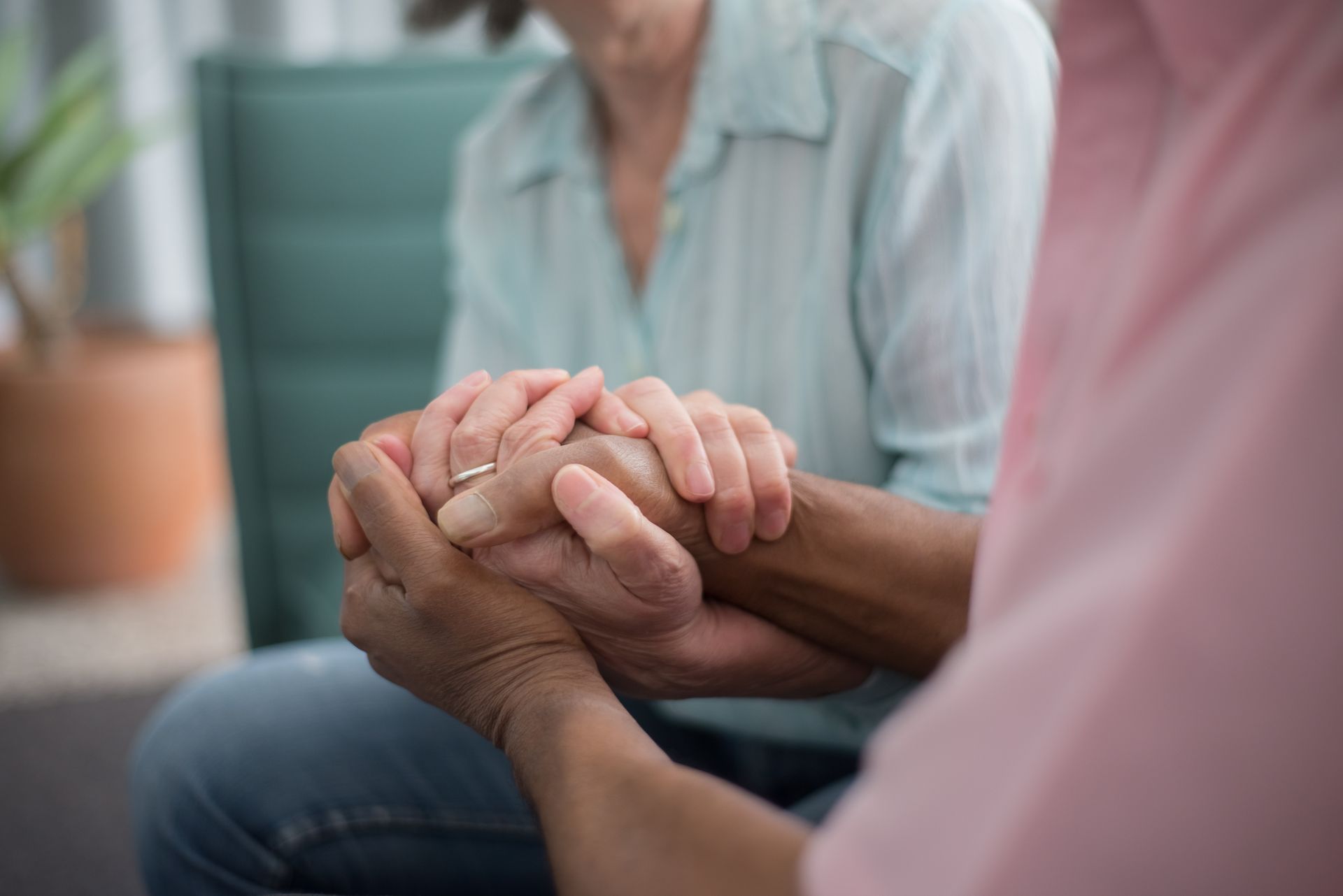 A man is holding a woman 's hand while sitting on a couch.