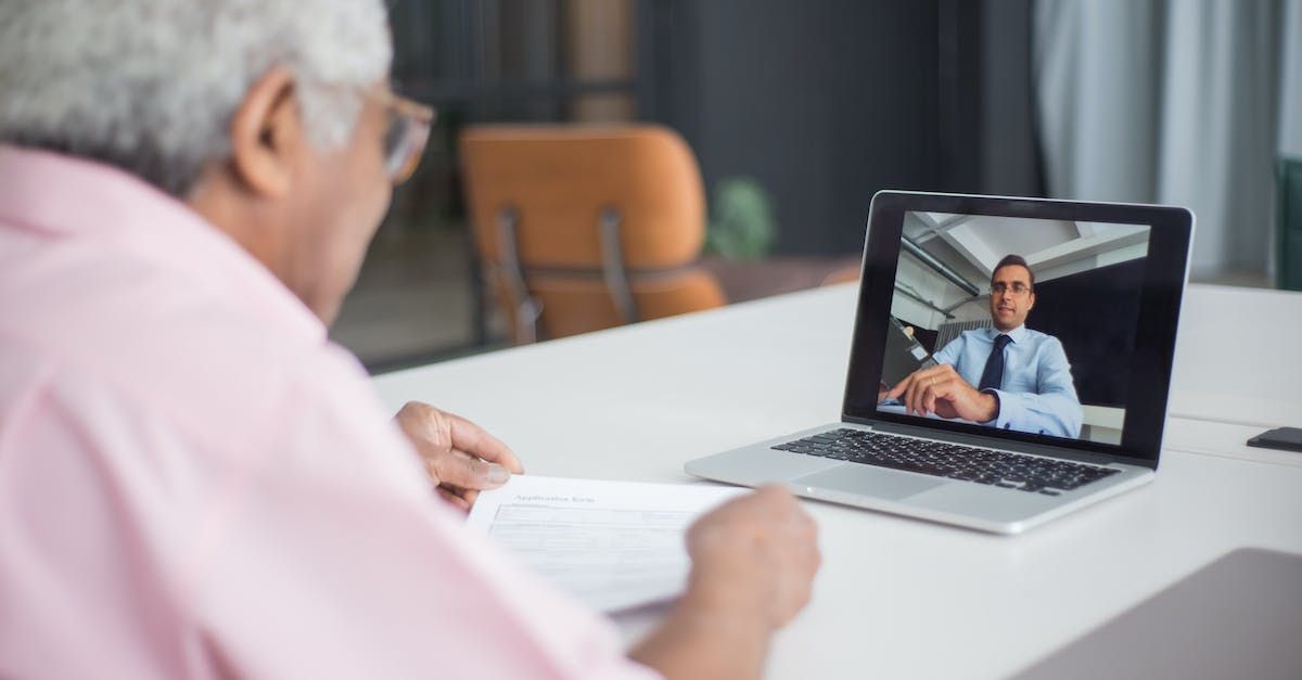 Um homem mais velho está sentado à mesa usando um laptop.