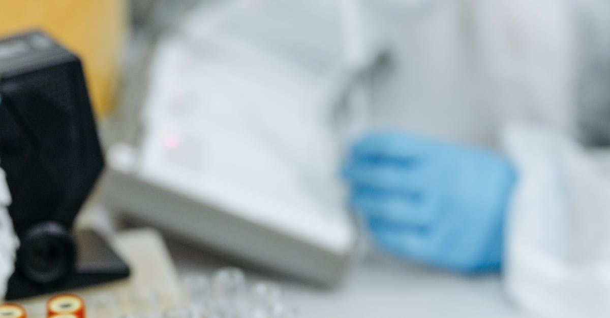 A blurred image of a person wearing blue gloves in a laboratory.