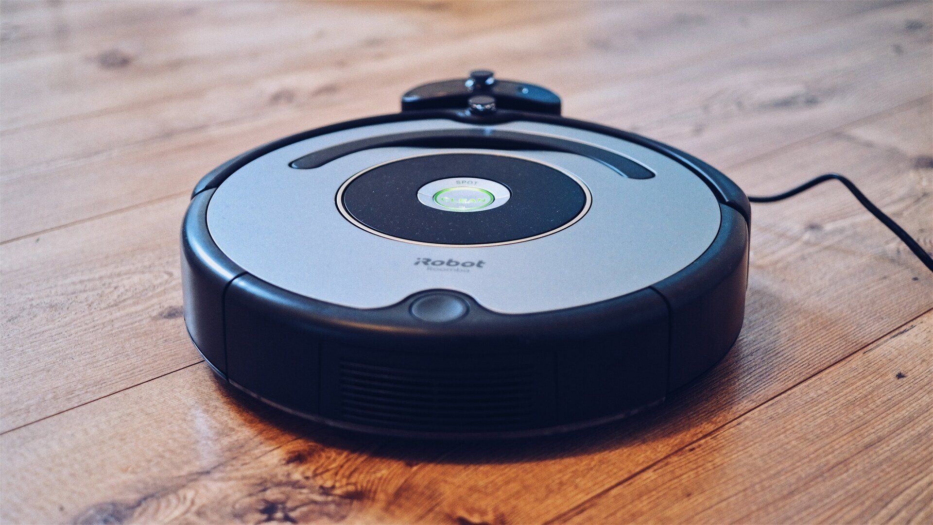 A robot vacuum cleaner is sitting on a wooden floor.