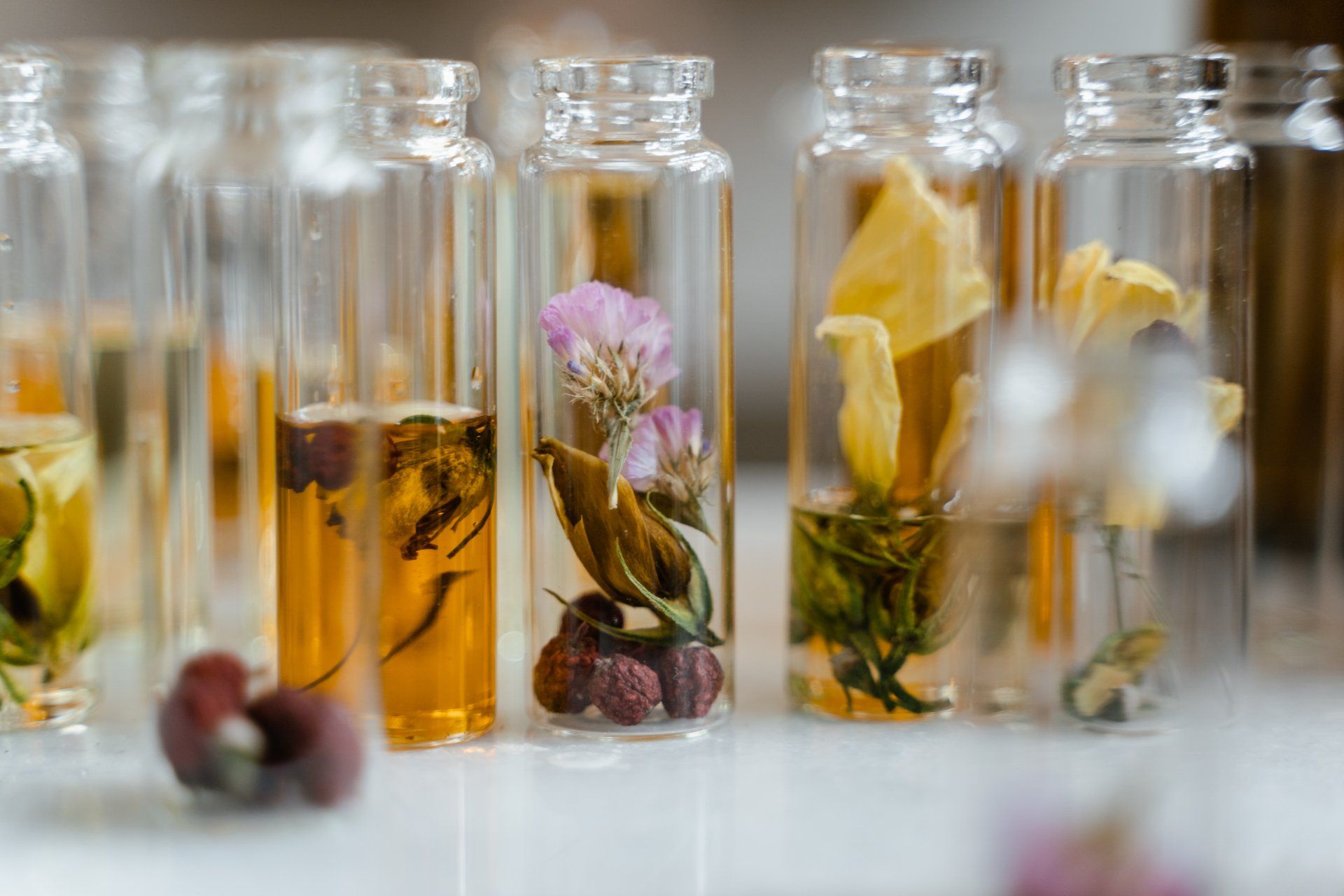 A row of bottles filled with different types of liquid and flowers.