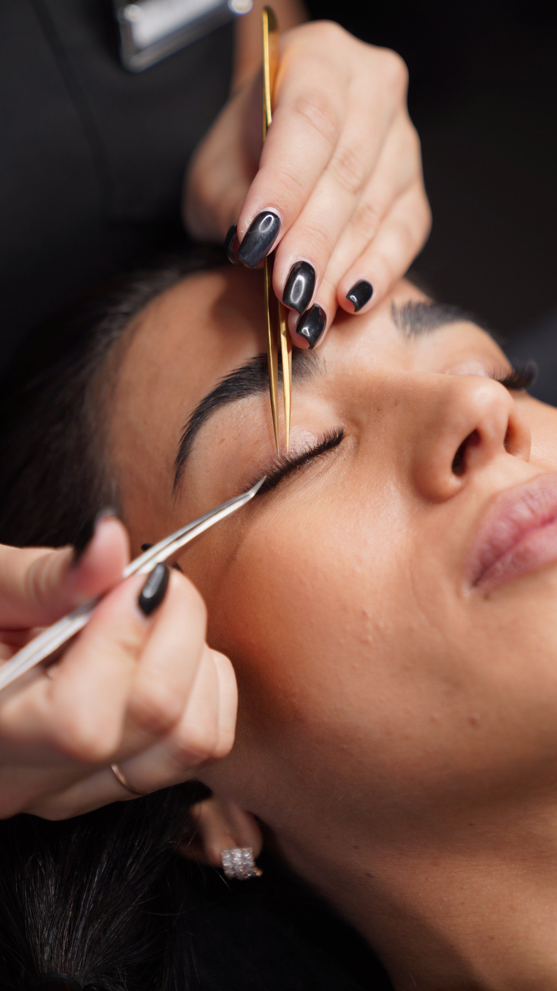 A woman is getting her eyebrows done by a makeup artist.