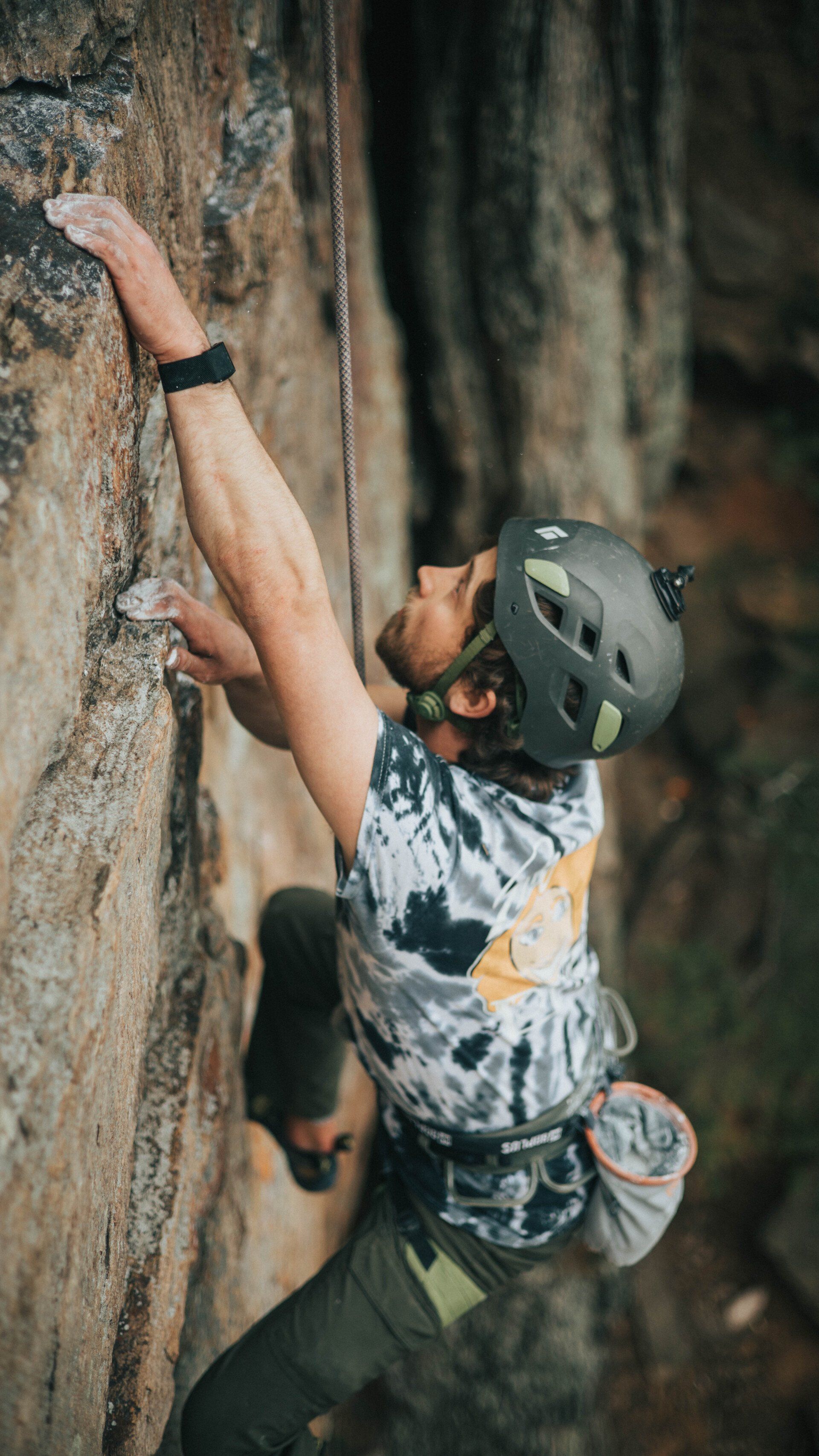A man wearing a helmet is climbing up a rock wall.