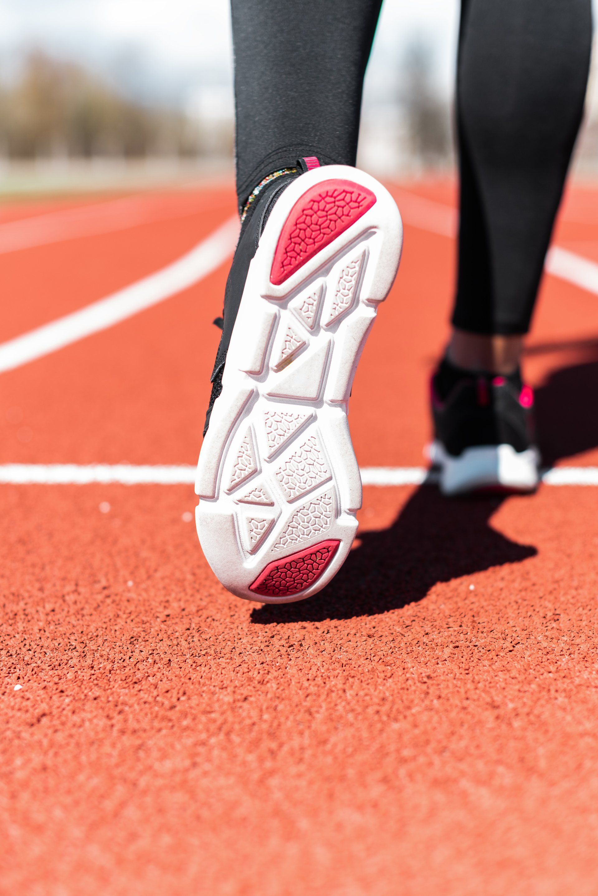 The bottom of a person 's shoe is shown while they are running on a track.