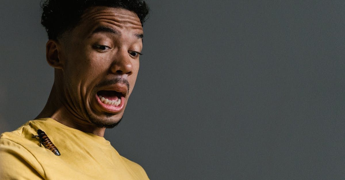 A man is looking at a cockroach on his shirt.