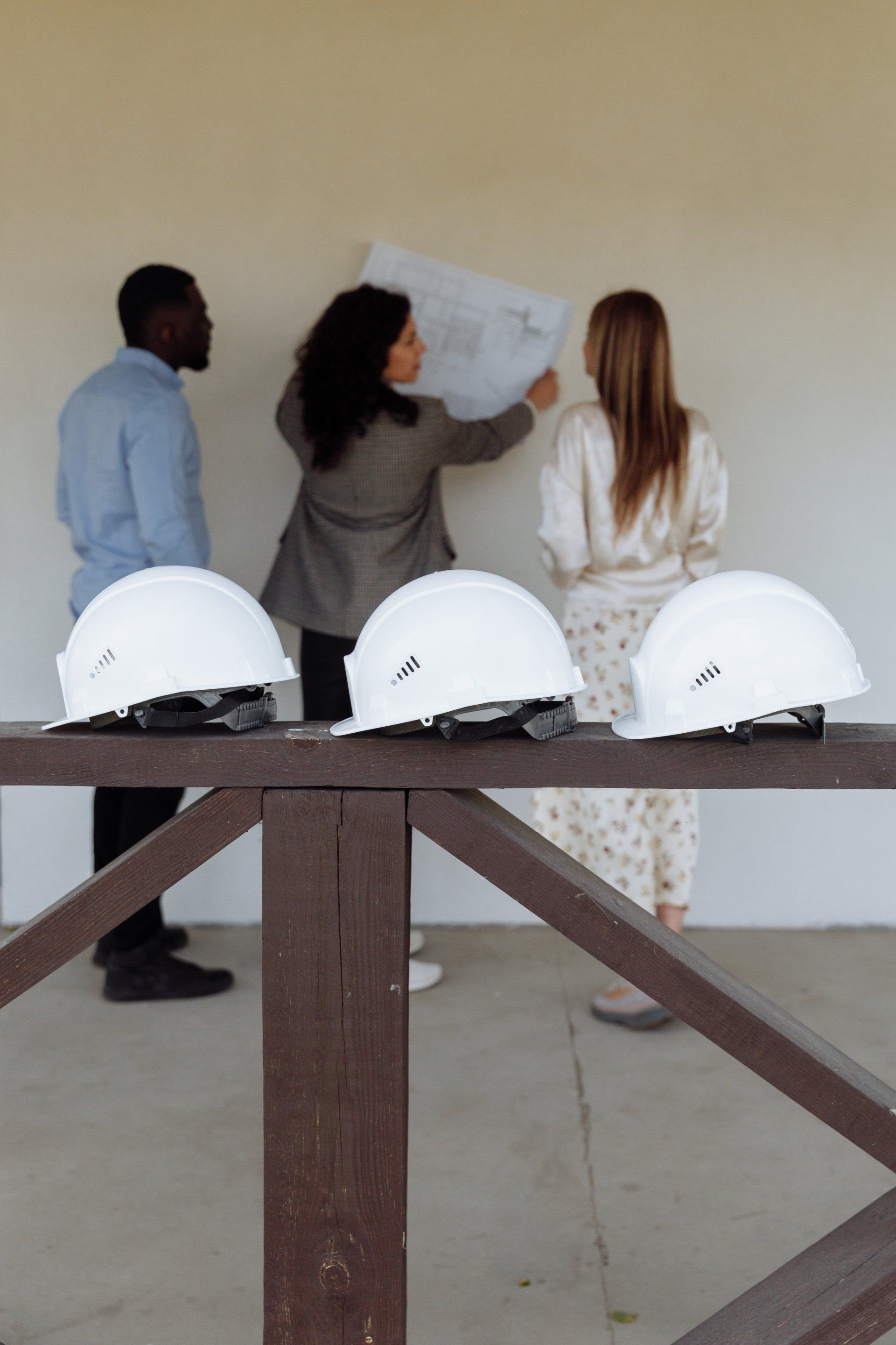 A group of people are standing around a table with hard hats on it.