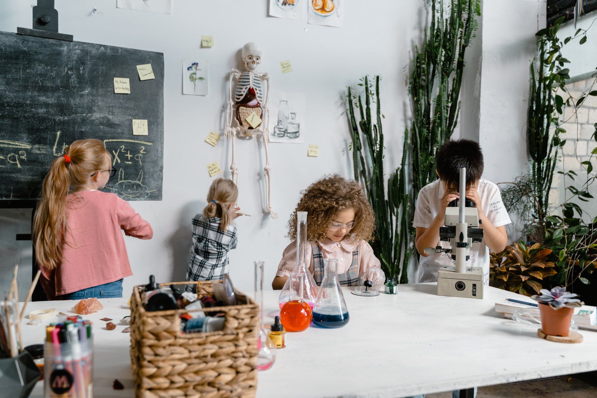 A group of children are sitting at a table looking through a microscope.