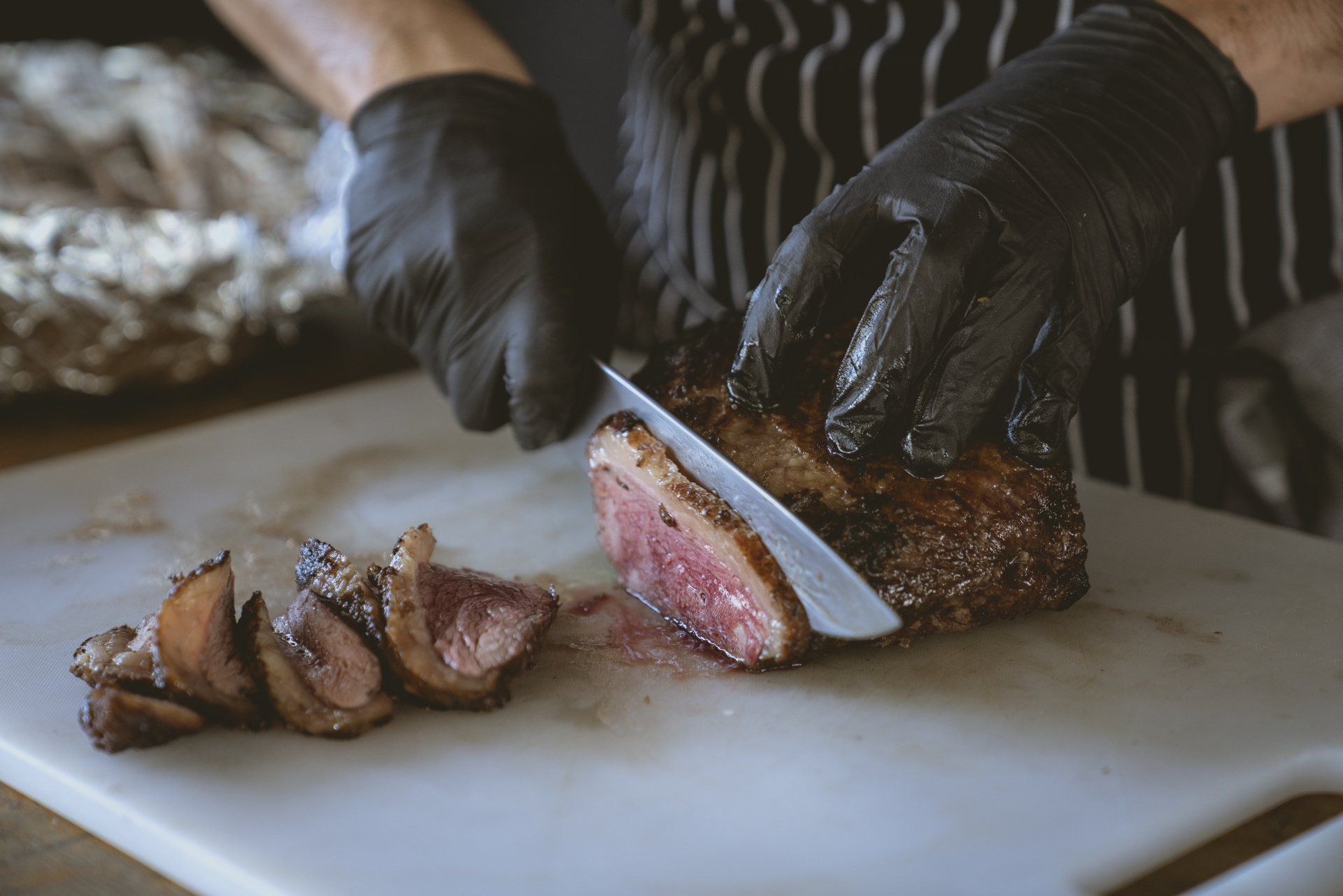 A person is cutting a piece of meat on a cutting board.