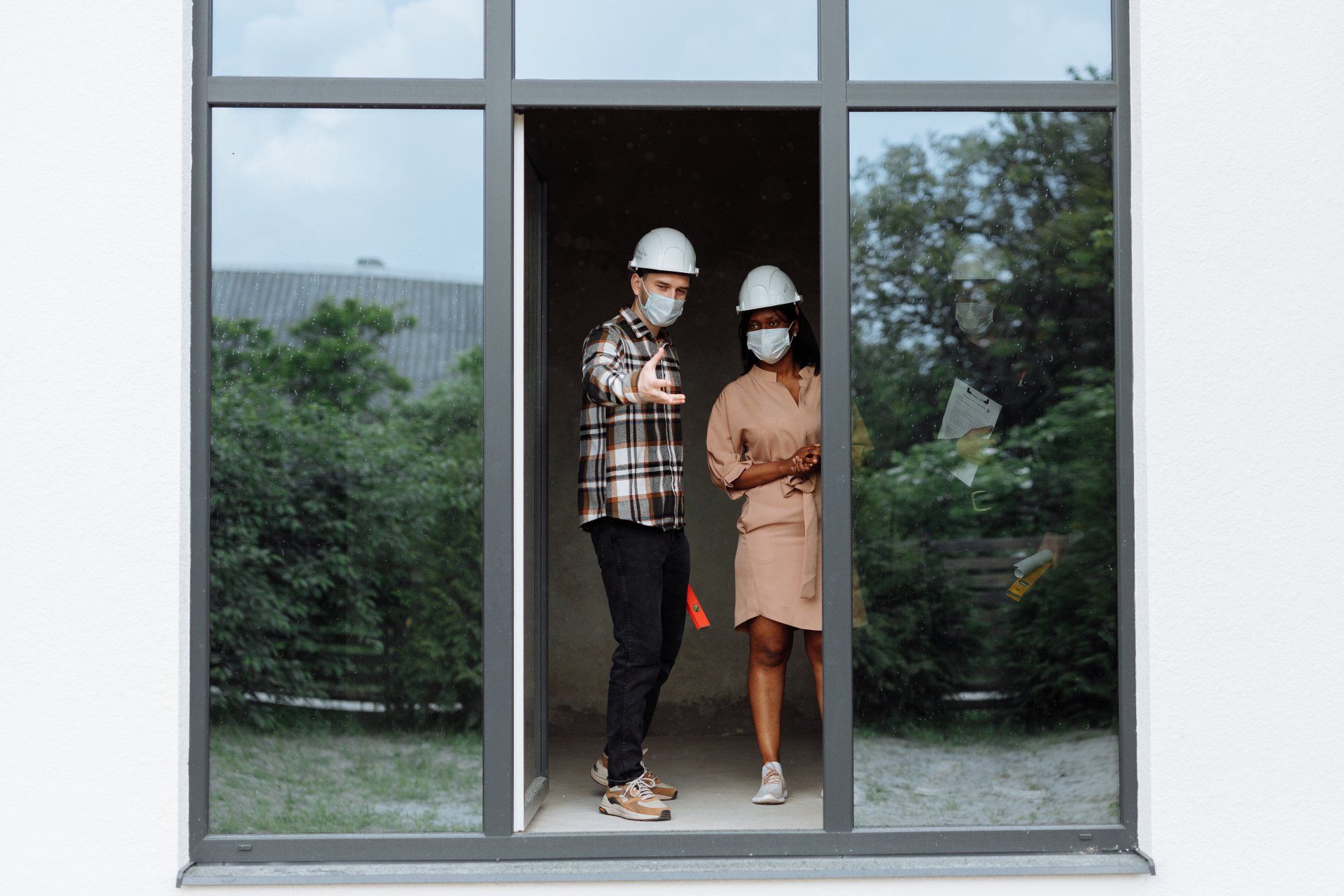 Two people standing in a doorway. They're both wearing protective gear as the house is being built.