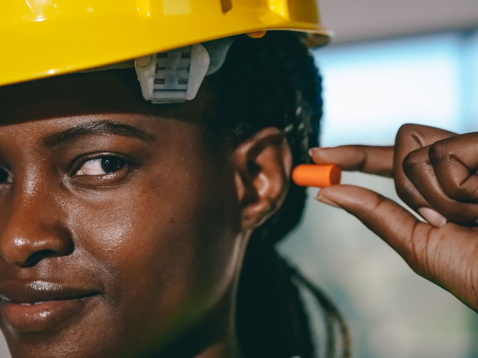 A woman wearing a hard hat and ear plugs