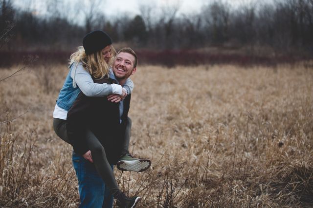 A man is carrying a woman on his back in a field.