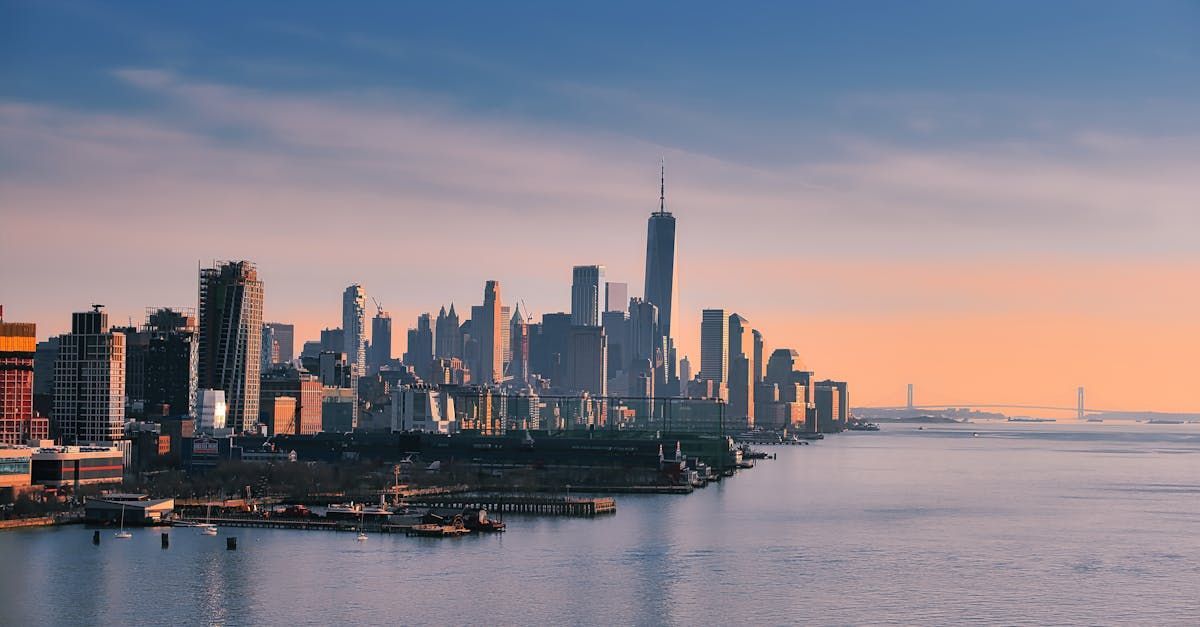 The skyline of new york city is visible over the water at sunset.