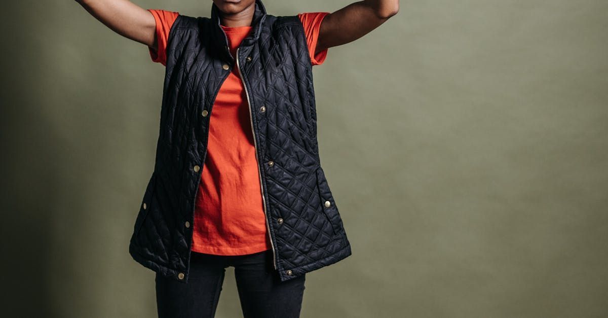Woman in orange shirt and black vest with arms raised.
