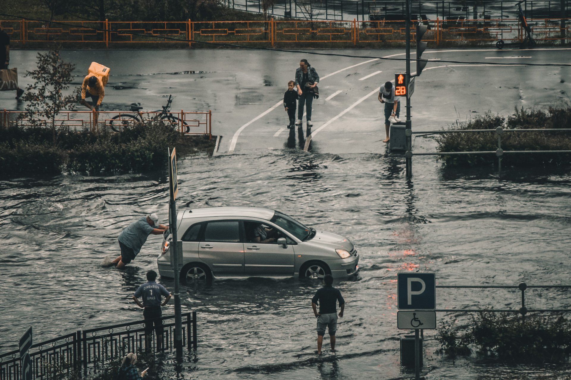 A car is driving through a flooded street.