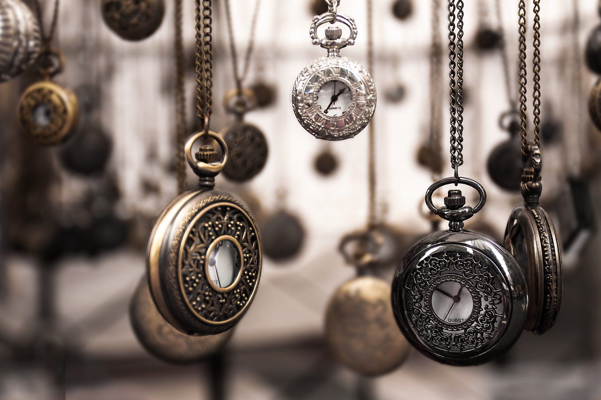 a group of pocket watches are hanging from chains .