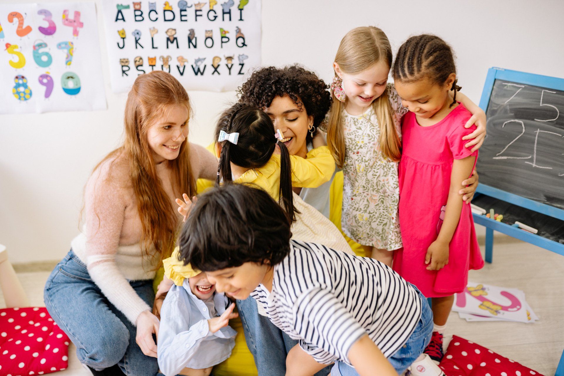 A group of children are playing with a teacher in a classroom.