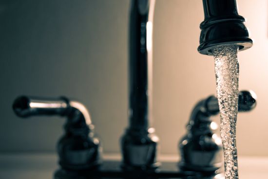 A close up of a faucet with water running out of it, indicating clean water from Cain Water Filters in St. Louis