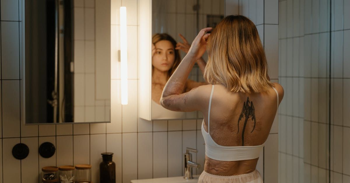 Woman with scarring on her back and arms looking into a mirror