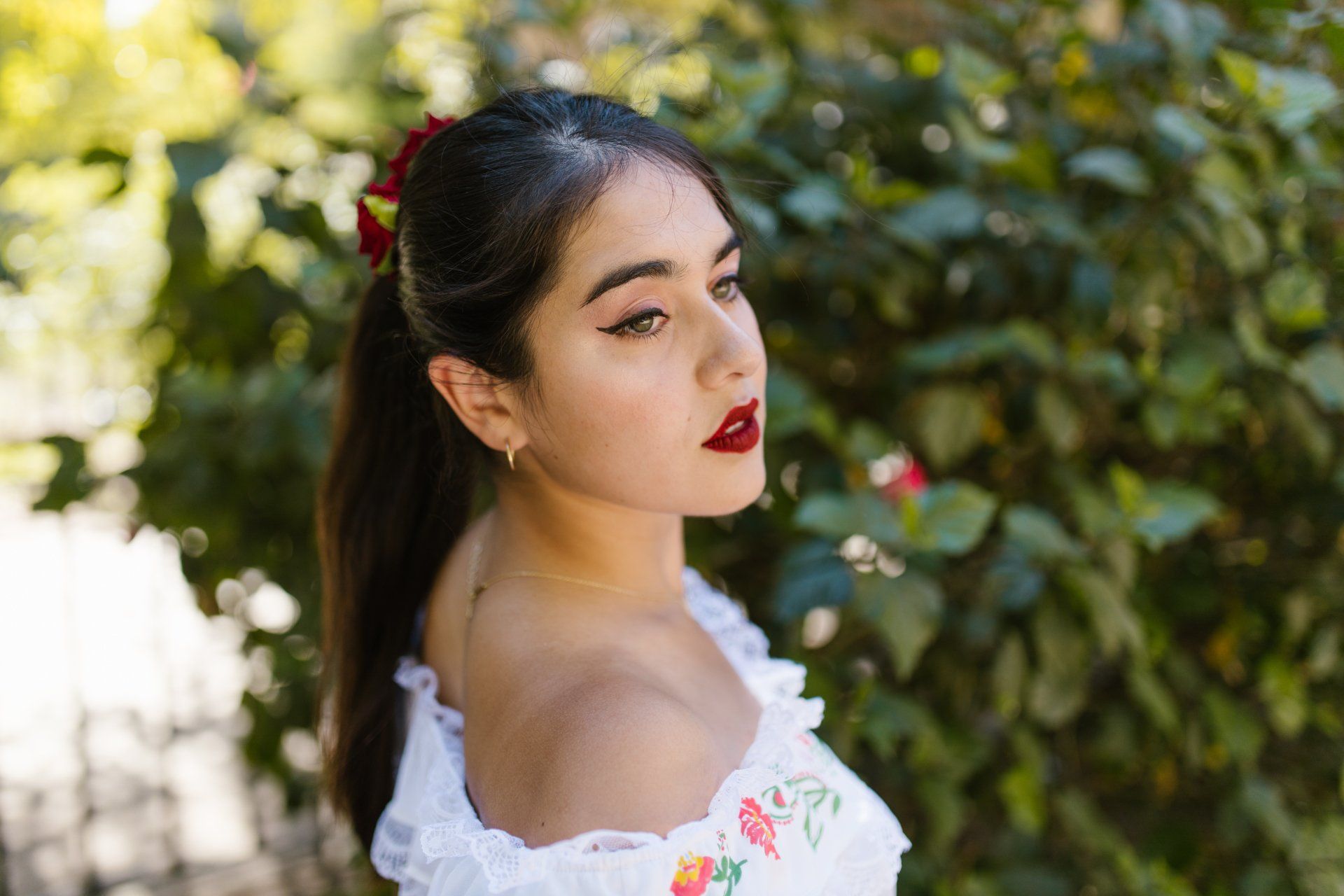 A side view of a beautiful  young Mexican woman in a white off-the-shoulder dress